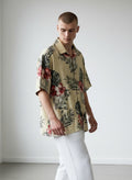 Caribbean cream silk and cotton blend Hawaiian shirt with red and white hibiscus flowers and green leaves.