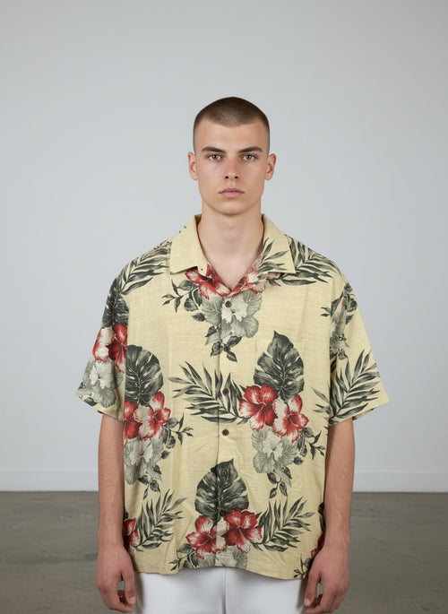Rewearz Hawaiian shirt with hibiscus flowers in cream, red, and grey on a light yellow background. 82% silk & cotton blend.