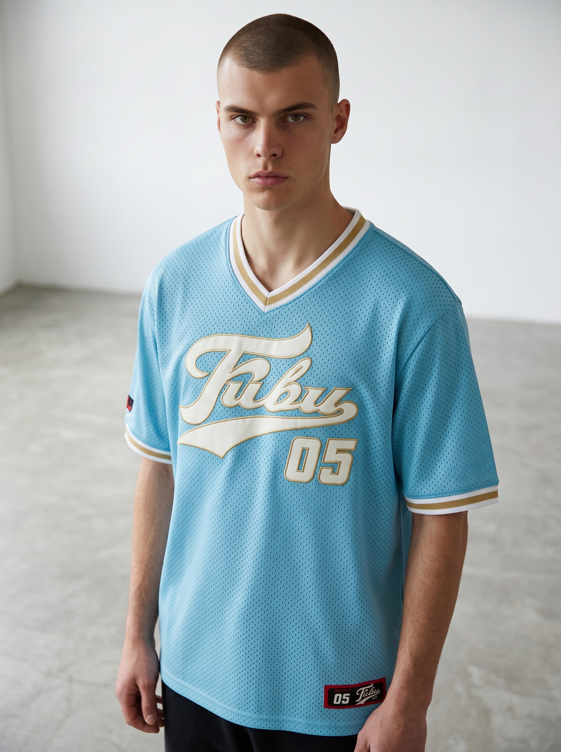 Rewearz light blue FUBU oversized baseball jersey with white and gold trim and embroidered FUBU logo and '05'.