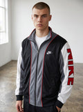 Rewearz vintage 90s Nike oversized tracksuit jacket in black, grey, and white with embroidered logo and red trim.