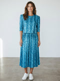 RewearzHere blue vintage 90s midi dress with leaf print, shoulder pads, and a flowing skirt.